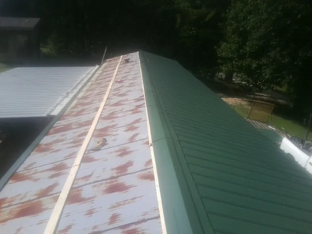 Old rusted panels beside newly installed green metal roofing — Wind Damage Roof Repair by Roofing Brothers in Coolidge