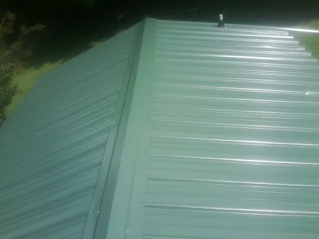 New green metal panels meeting at the ridge of a roof — Flat Roof Repair work by our crew in Coolidge