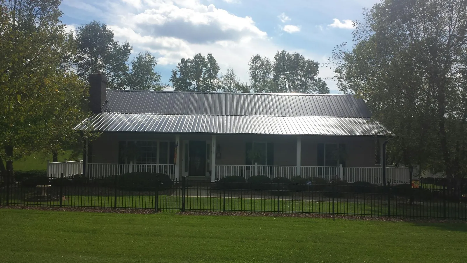 Gray metal roof on a brick ranch with a full width front porch — Gutter Guard Installation work by our crew in Coolidge