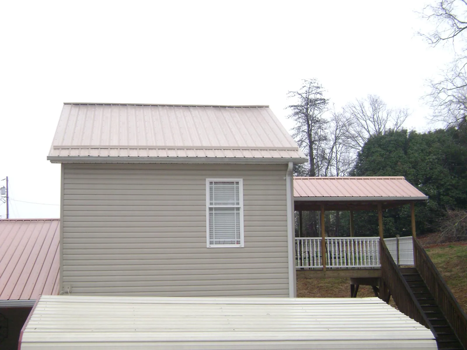 Tan metal roofs on a two story addition and attached porch, from a Roof Replacement job in Coolidge
