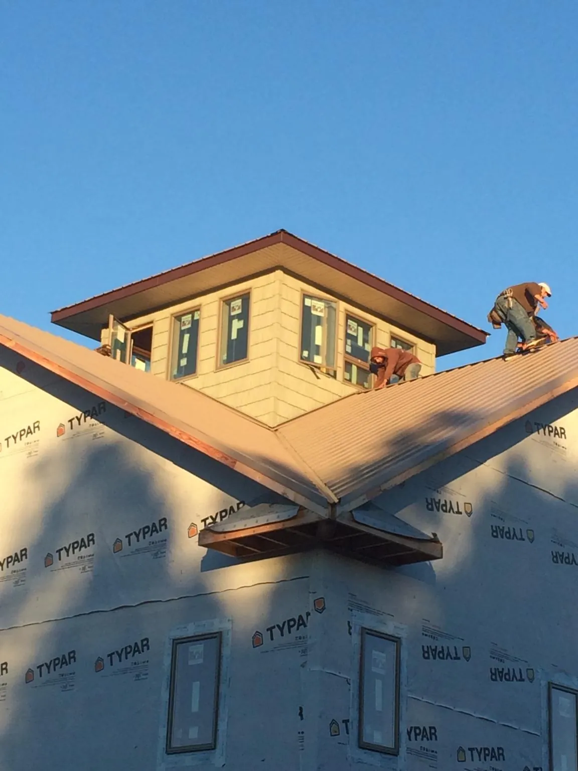 Roofers working around a rooftop cupola on a new metal roof at sunset — Roof Waterproofing in Coolidge by Roofing Brothers